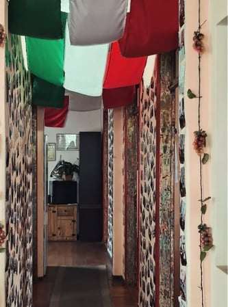Corredor decorado com bandeiras da Itália no teto e cachos de uvas nas paredes