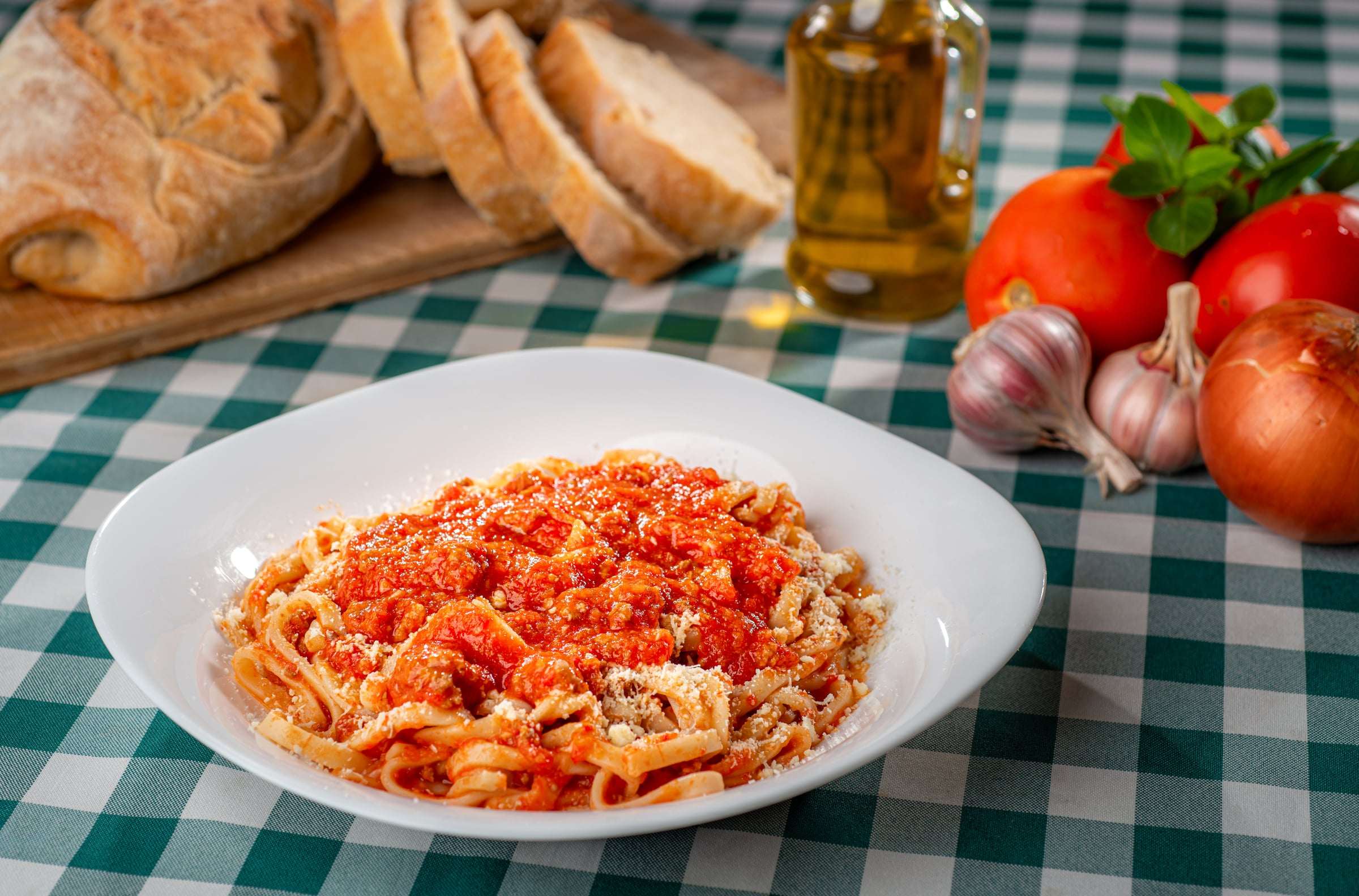 Massa longa ao molho de tomate com carne em prato fundo branco