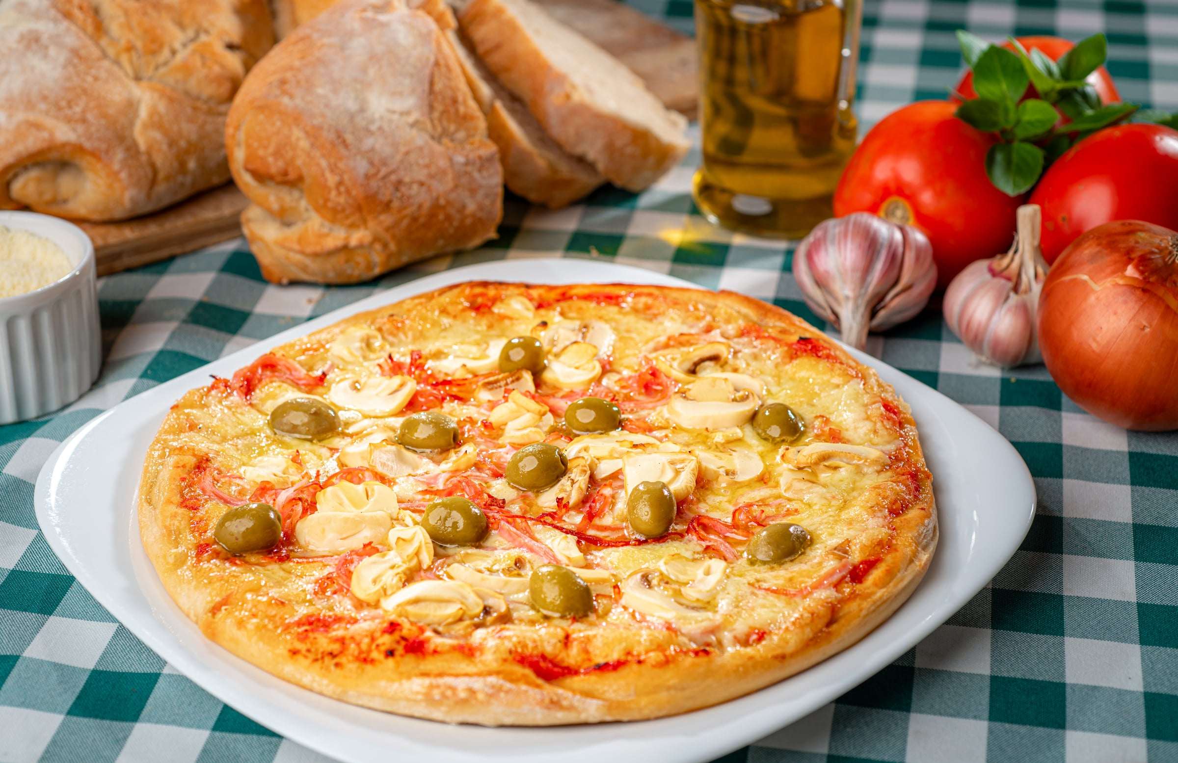 Pizza com queijo gratinado e azeitonas verdes em prato branco