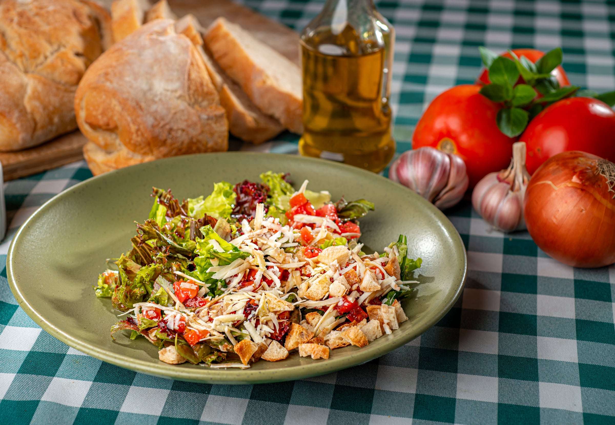 Salada de folhas com tomate, lascas de parmesão e croutons em prato verde